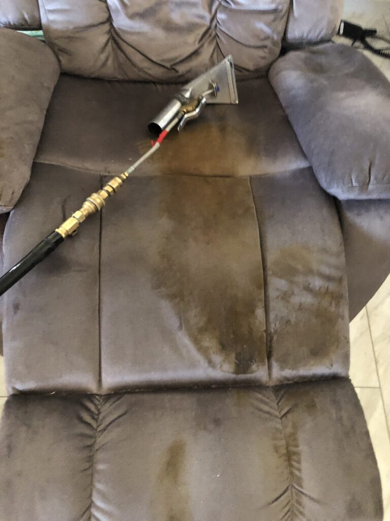 A cleaning wand on a stained sofa.
