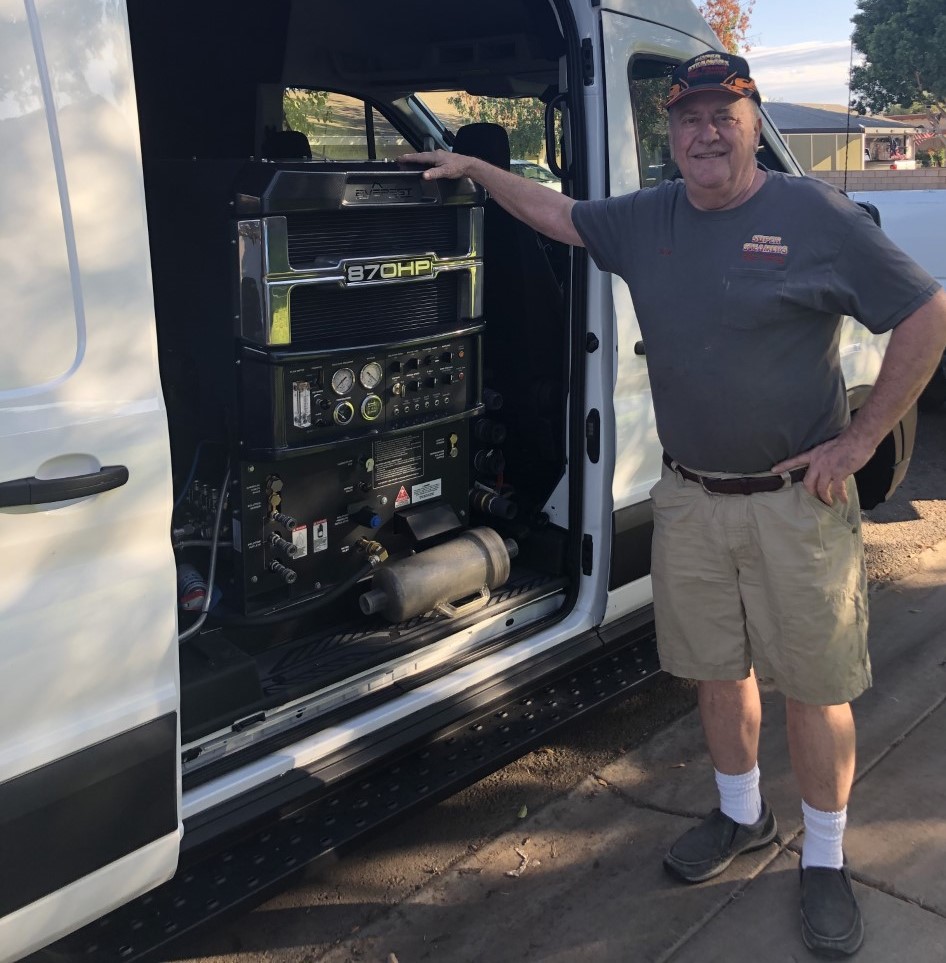Man standing next to an open van with electronic equipment inside.