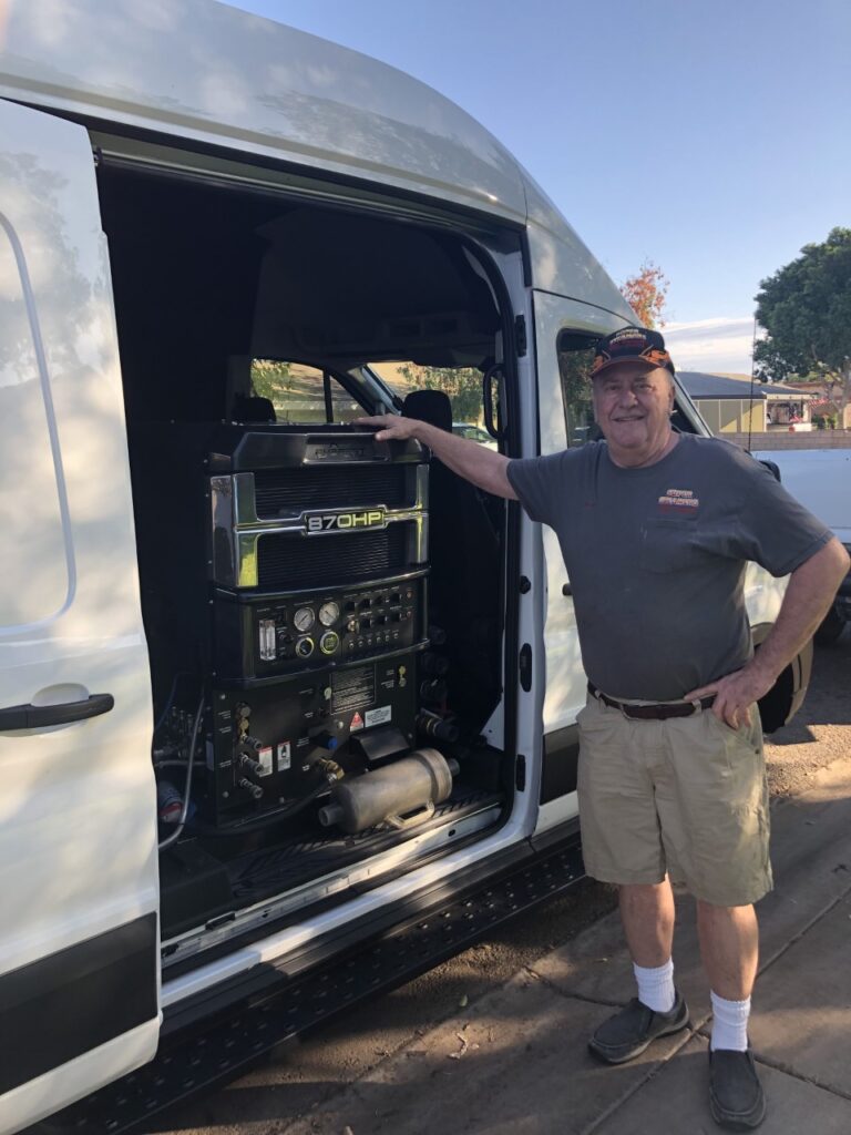 Man standing next to a van with audio equipment inside.